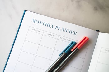 an open planner with pens beside it