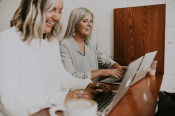 two women looking at laptops