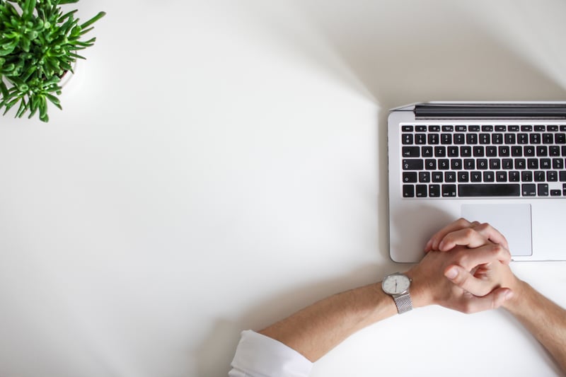 hands folded on top of an open laptop