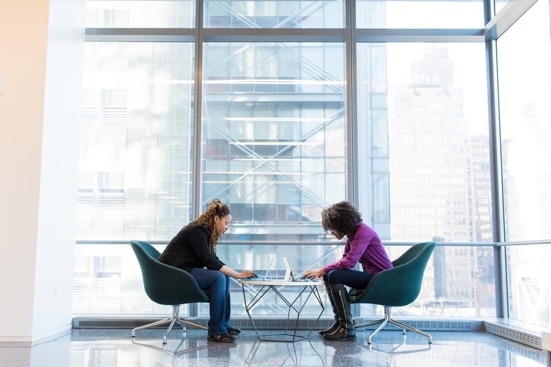 two women working on laptops at a table 